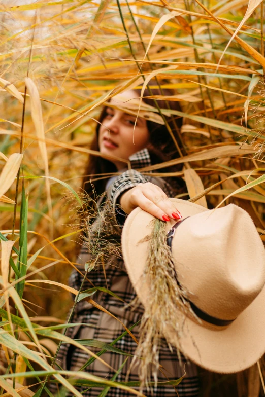 a girl with a hat in a field of long grass