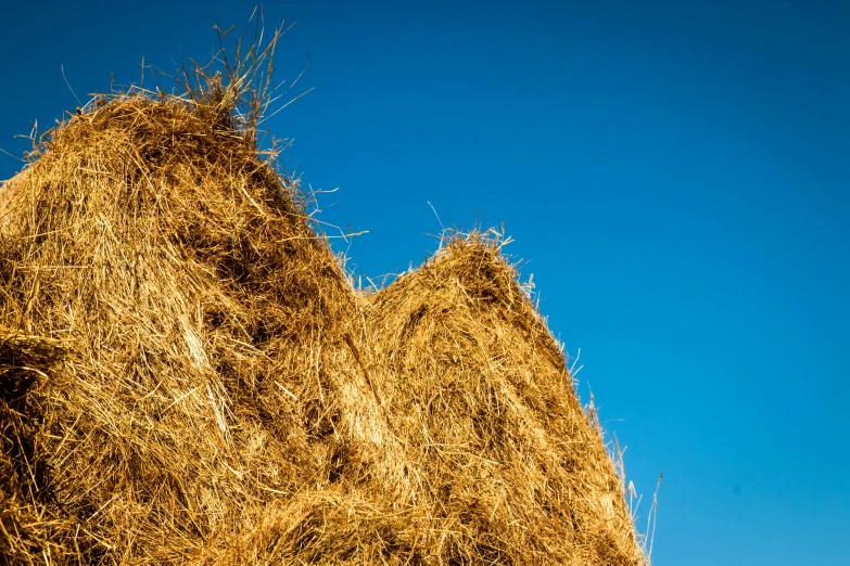 a blue sky with no clouds and a large pile of hay