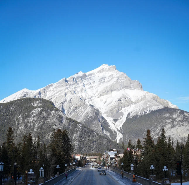 cars are driving on the road while mountains are covered in snow