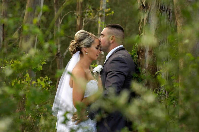 a couple is standing in the woods emcing