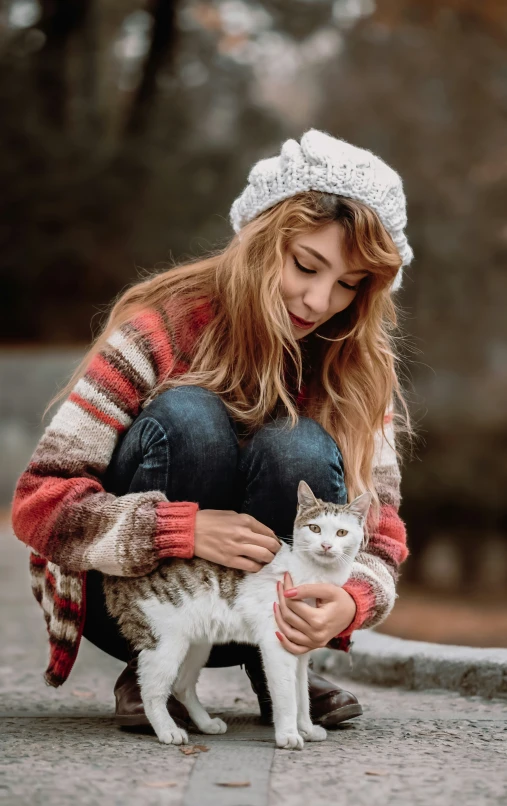 a woman sitting on the ground holding a cat