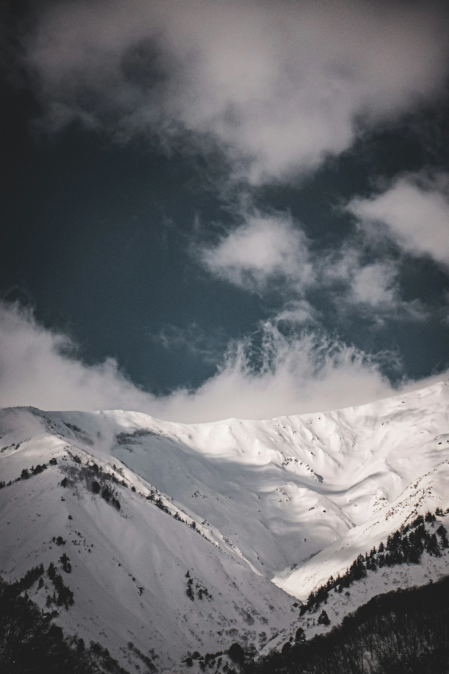 a cloudy day in the mountains with snow capped peaks