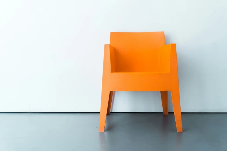 a modern yellow chair sits against a white wall