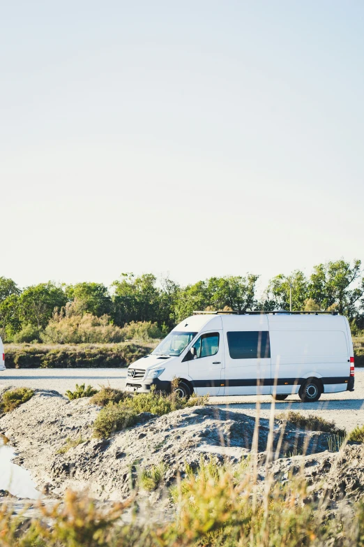 a van sits in the sand next to another van