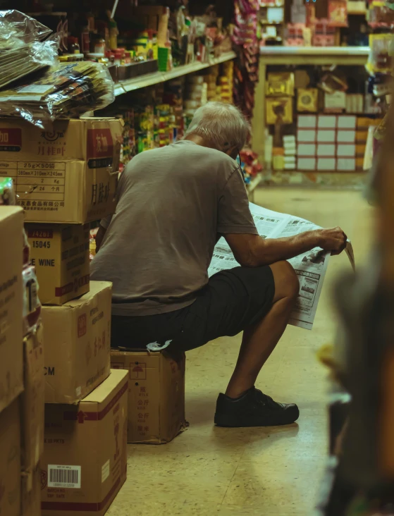 an older man sitting on a wooden bench reading the newspaper