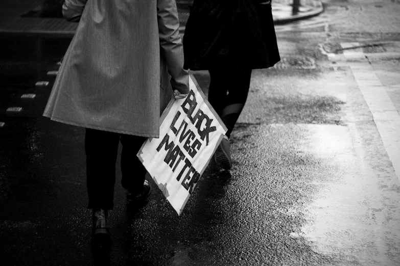 two people are walking down a wet city street