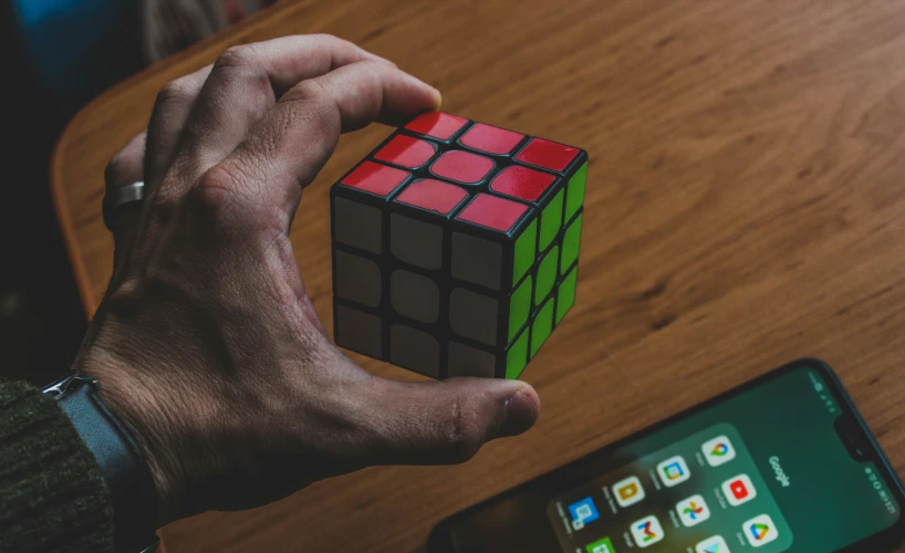 a person is holding a rubot cube next to a smart phone