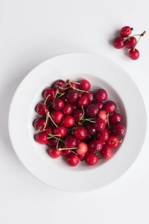 a plate filled with lots of cherries on a table