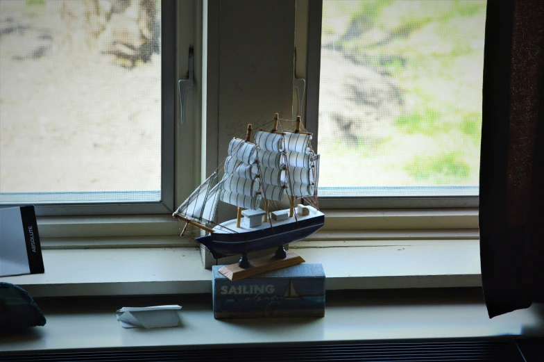 a toy ship that is sitting in the window sill