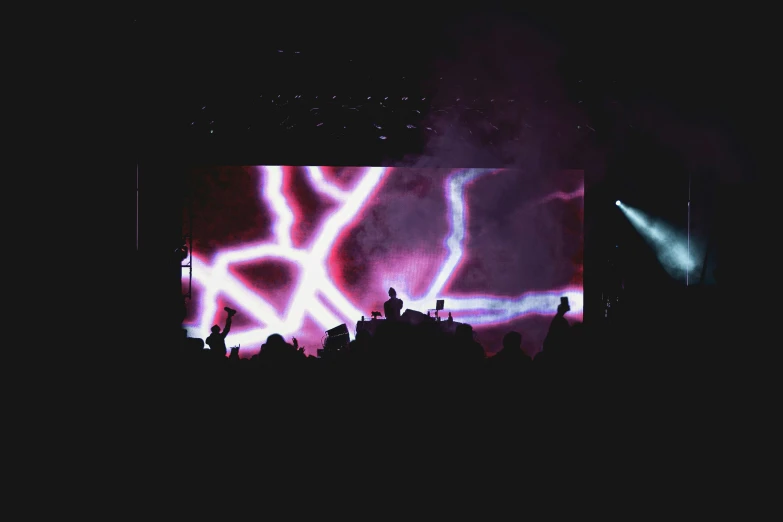 people are watching a bright screen at a concert