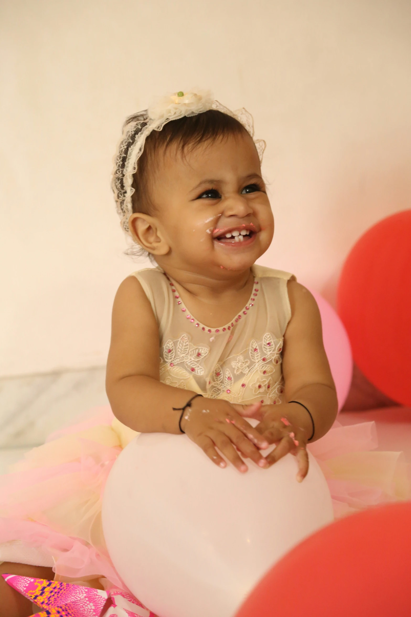 a smiling baby sitting with a bunch of balloons