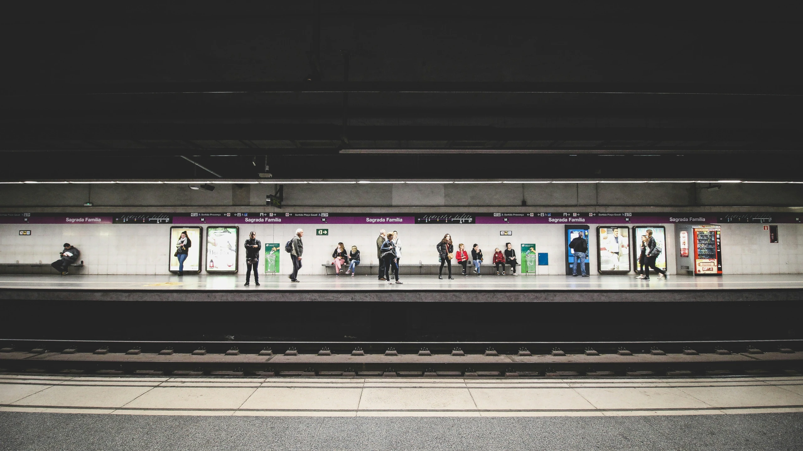 people standing in a subway station with trains and signs