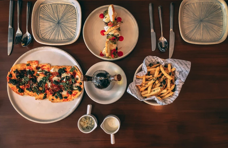 two white plates topped with pizza and fries