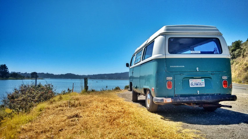 a van is parked in the grass by the water
