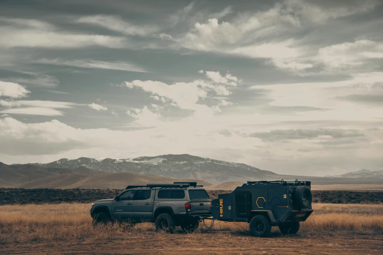 two cars sit on the dirt in a wide open field