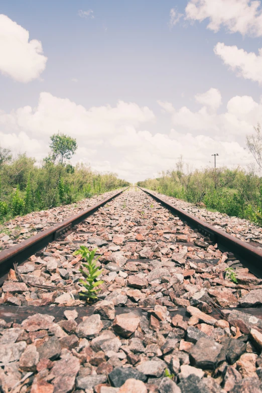 the view down a railroad track with rocks