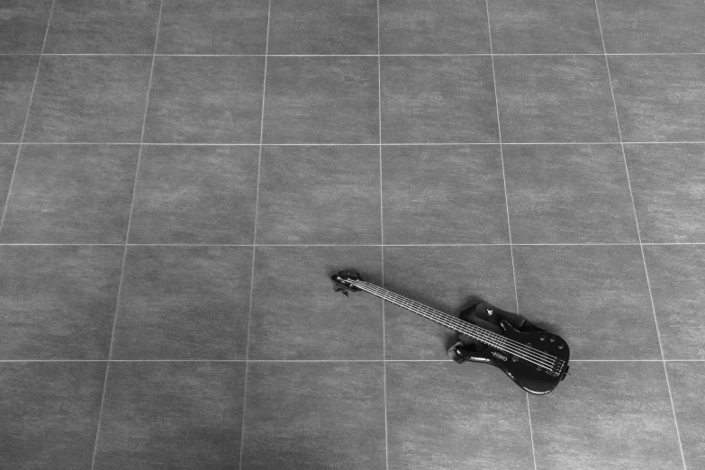 black and white pograph of guitar on a tile floor