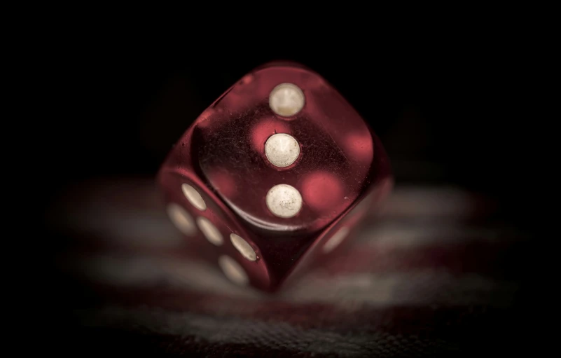 a red dice on a black background, with three white dots