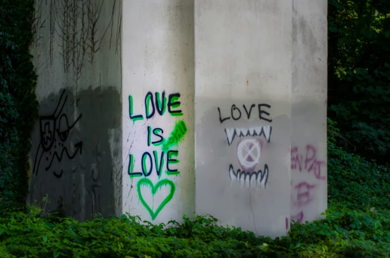 graffiti spray painted on three cement pillars with words love and love below