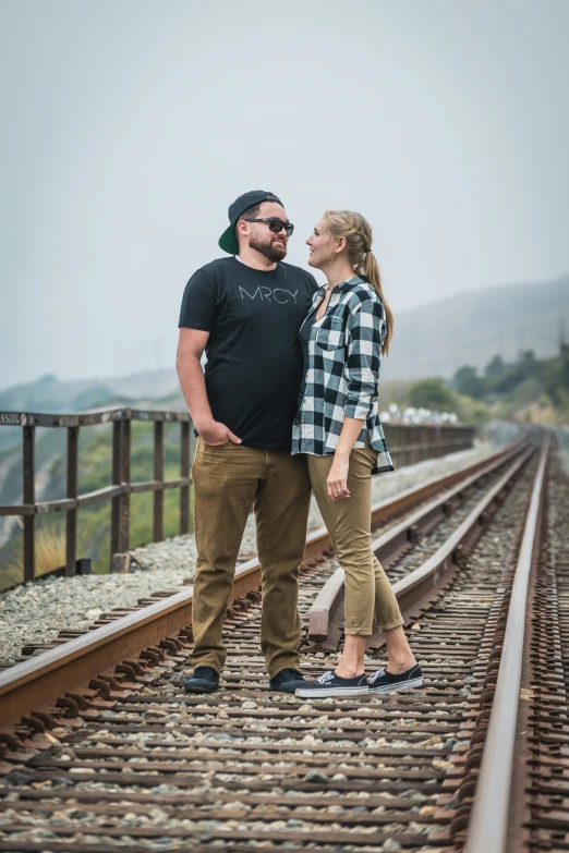 man and woman are standing on a train track