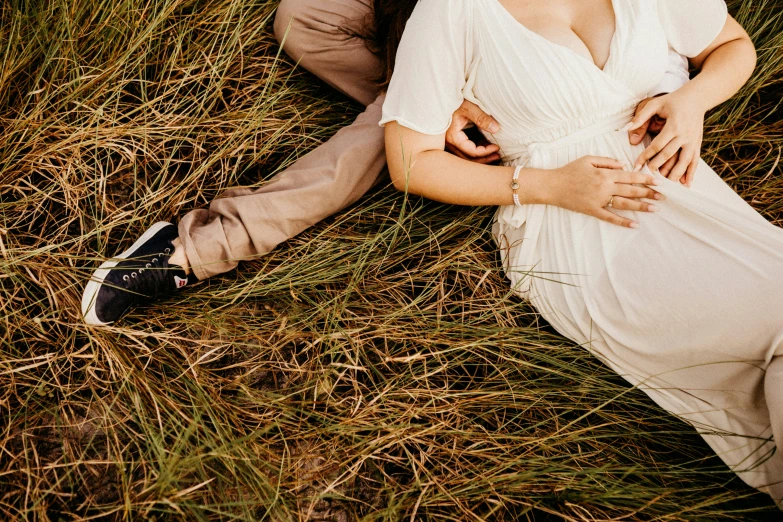 a beautiful woman laying next to a man in a field
