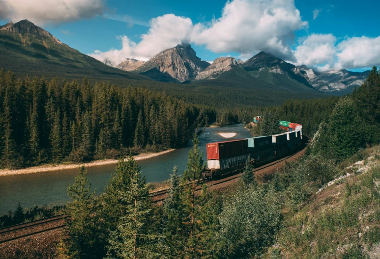 a train traveling down tracks near tall mountains