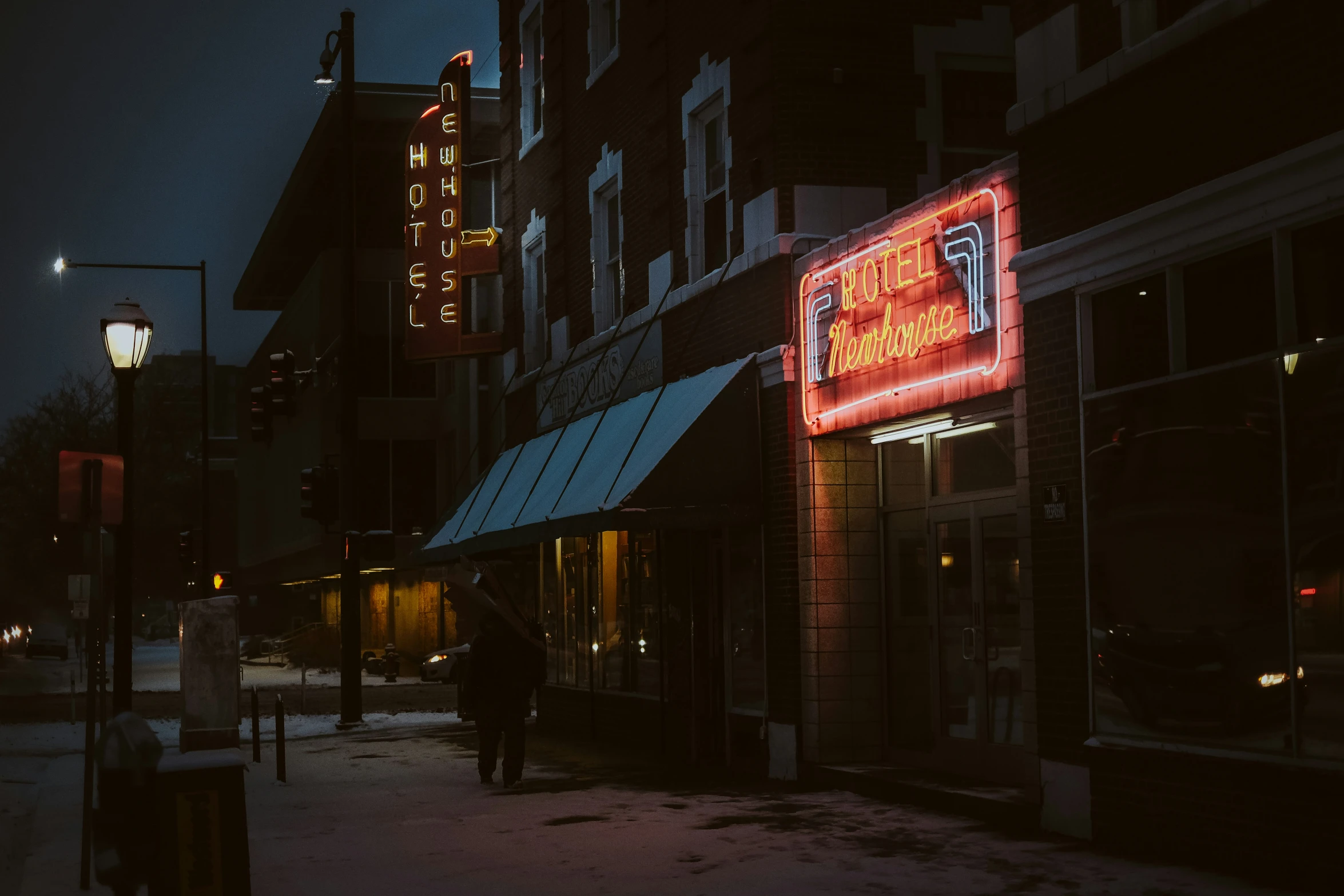 a dark city street with a neon sign on the building