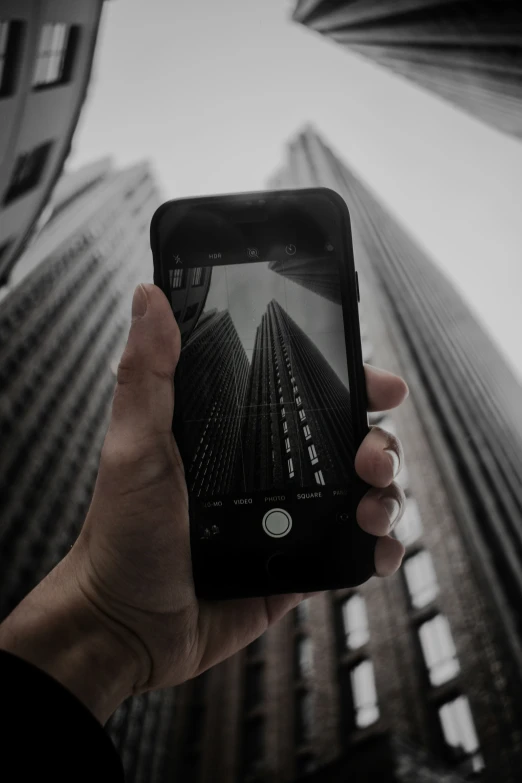 a person holding up a cell phone in front of a tall building