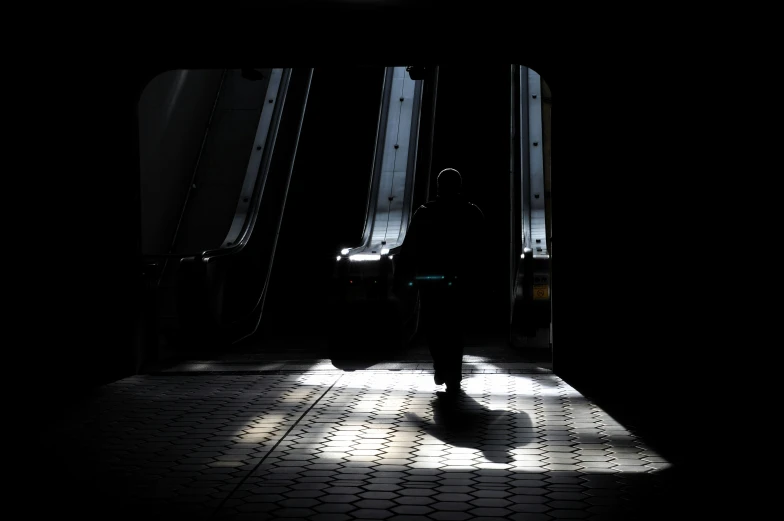 a man walking across an escalator in the dark