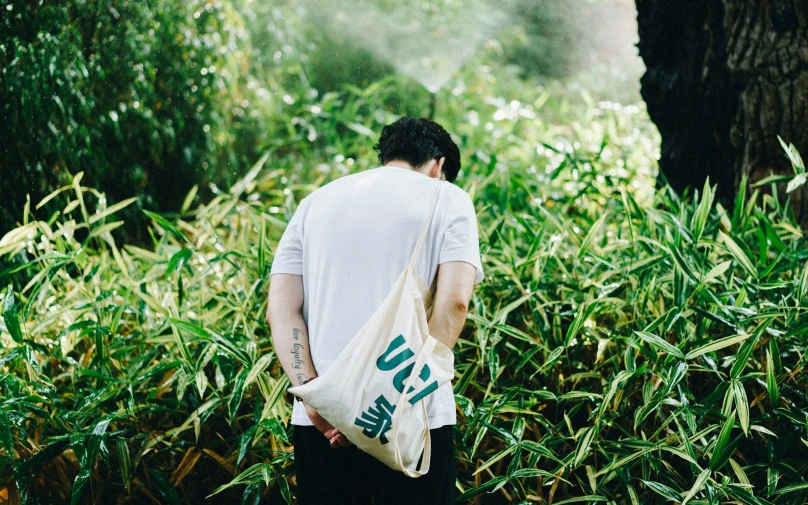 man in white shirt carrying a bag with blue writing on it