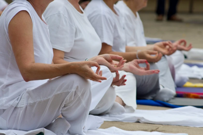 a row of people sitting on a floor with their hands together