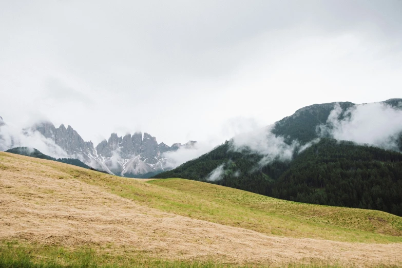 some mountains and grass with clouds on them