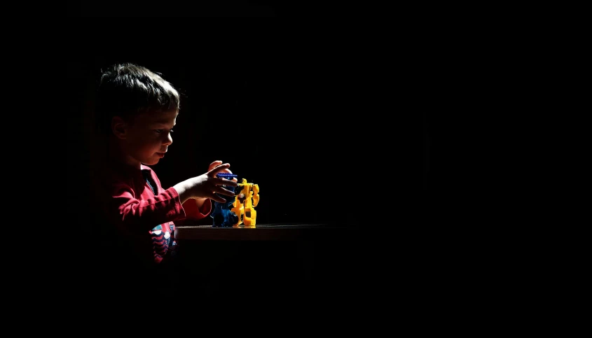 a child playing with legos in a dark room