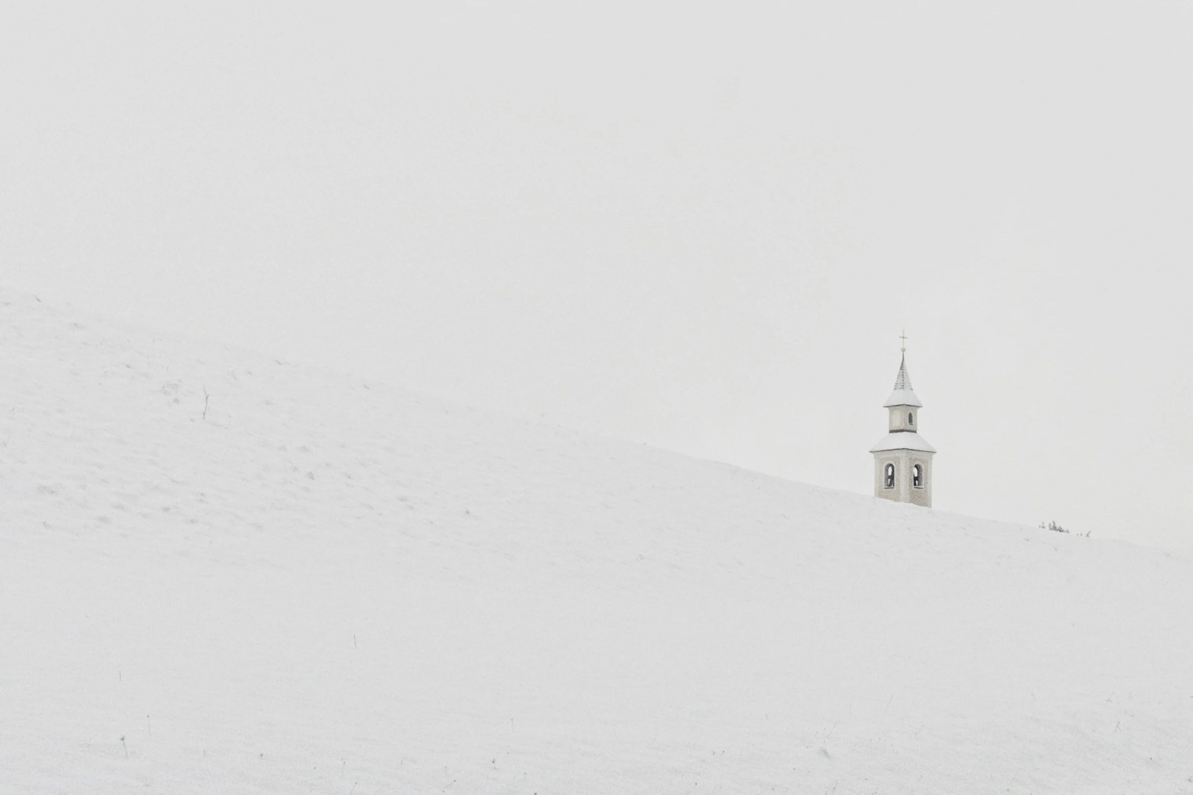 the white lighthouse tower is sitting on the hill in the snow