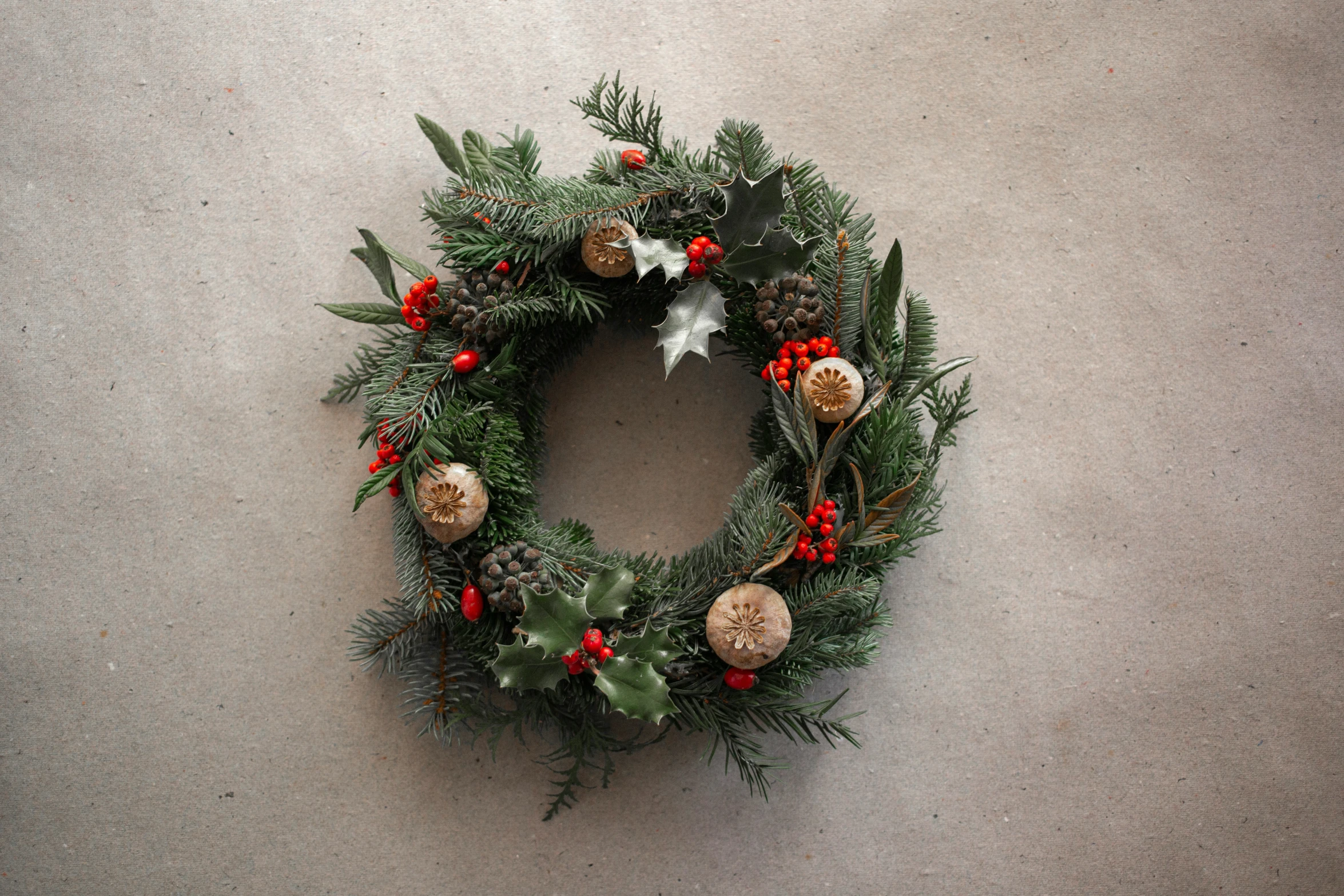 a wreath that has evergreen, pine, holly and mist