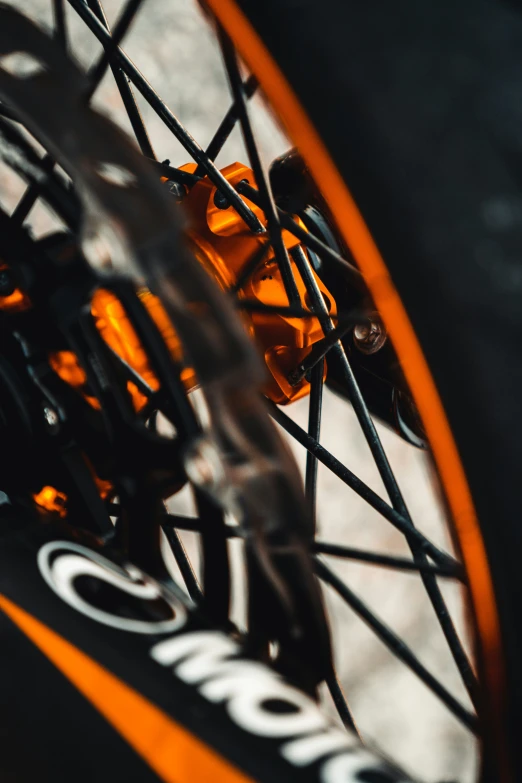 the rear wheel of an orange bicycle with spokes