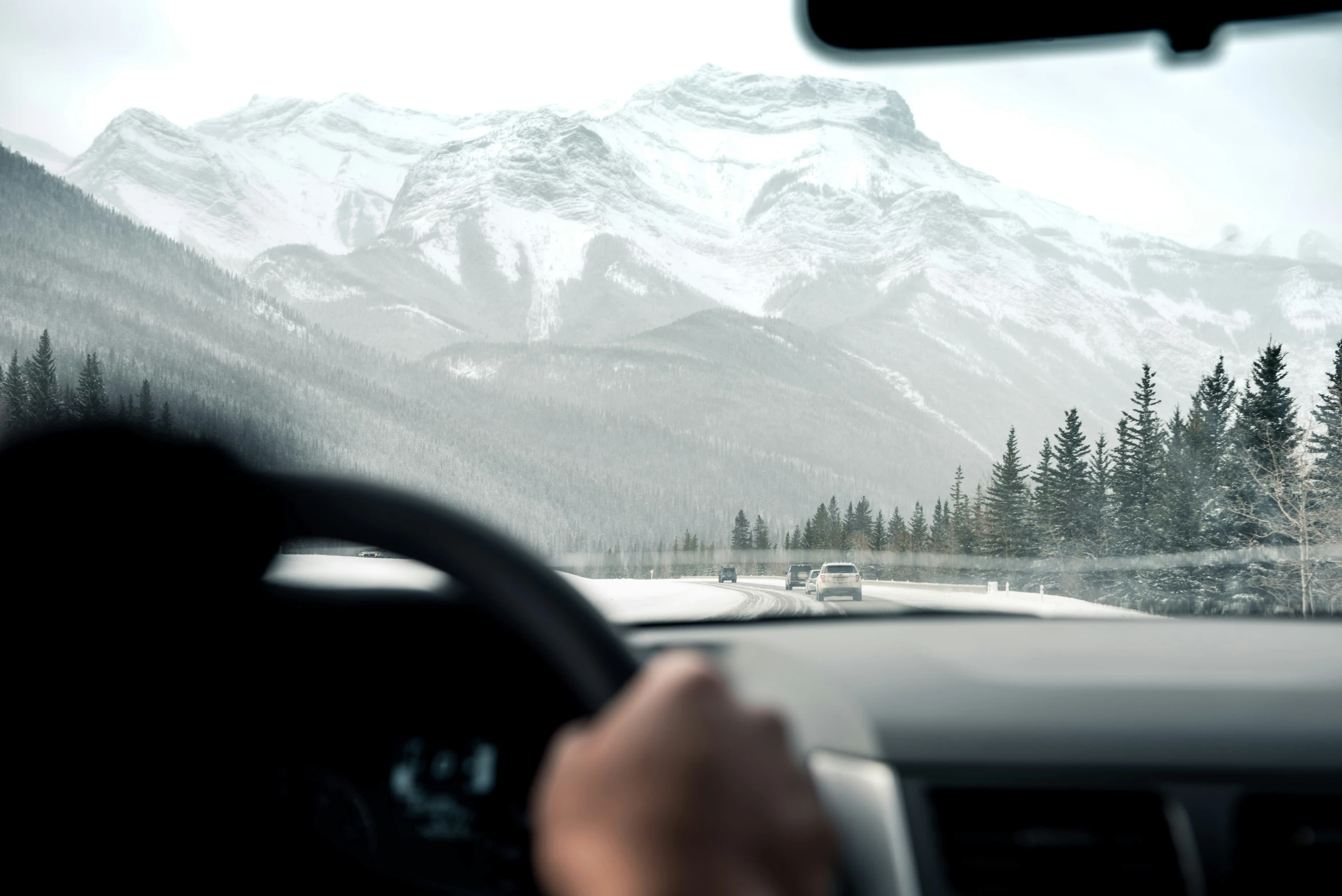 a road with snow covered mountains behind it