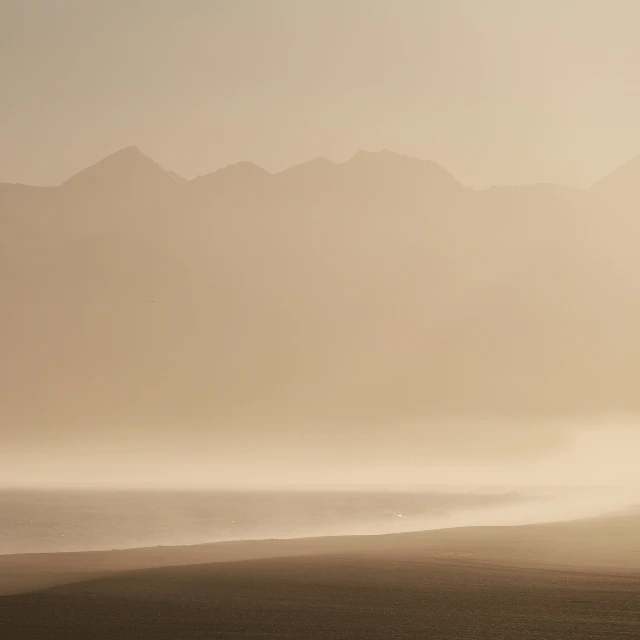 a boat on the shore near mountains in the fog