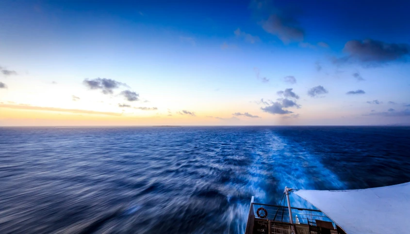 the wake of a boat near a rocky beach