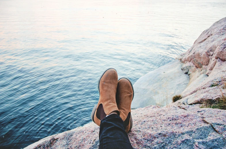 someone looking out over the water from atop a cliff