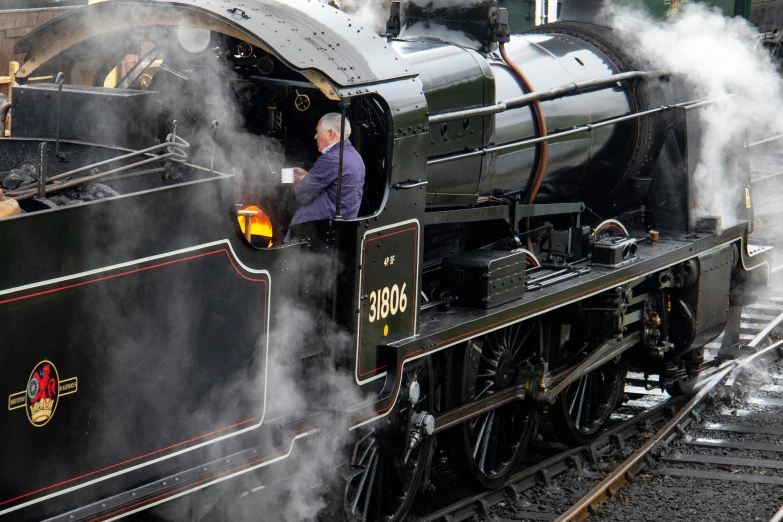 a man sitting inside of a black train engine