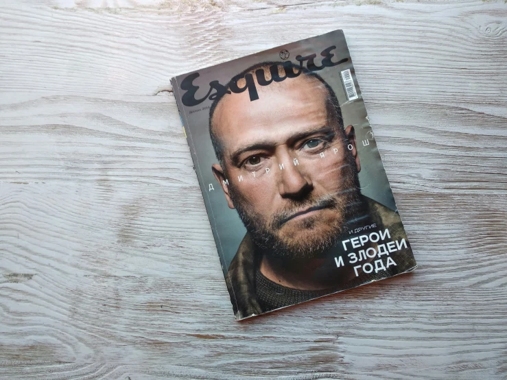 a magazine laying on a white surface with an image of the man wearing glasses