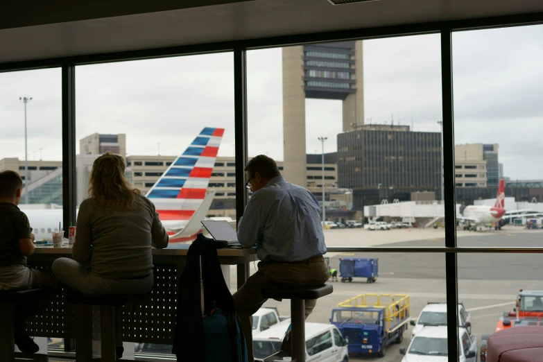 three people at a table waiting for their plane to come in