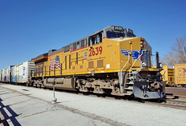 a freight train sits on the tracks beside other cars