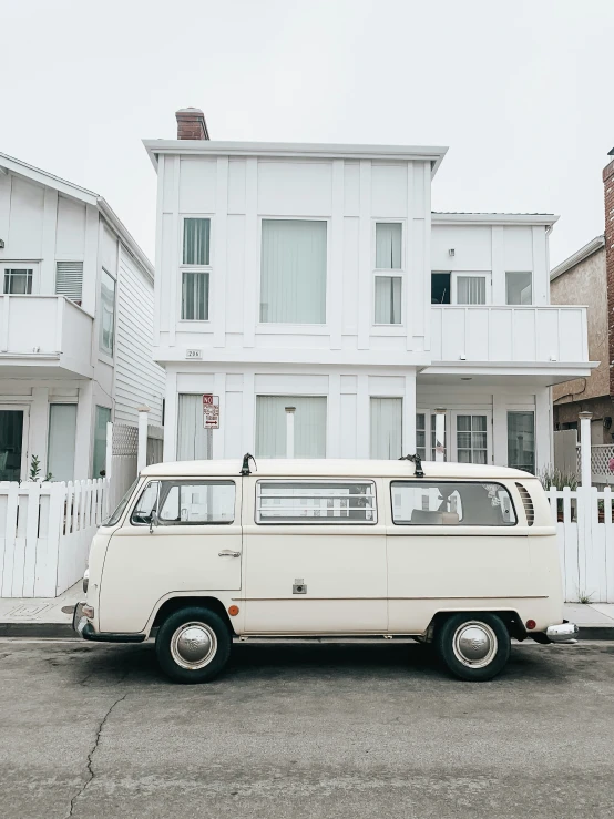an old van is parked on the street in front of a large house