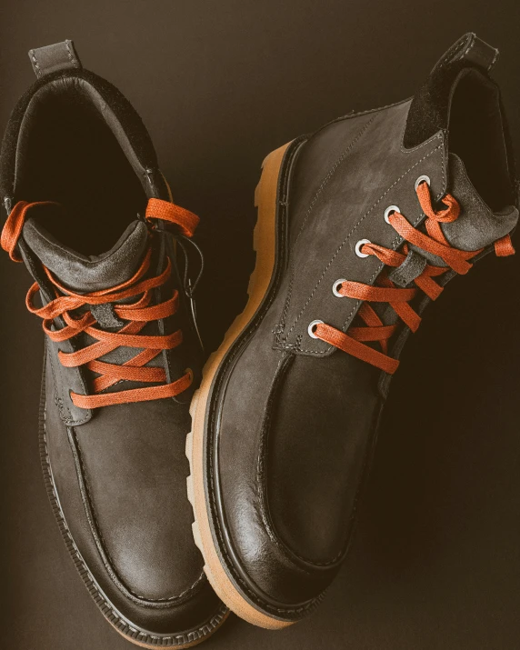 two black and orange shoes sit on a black surface