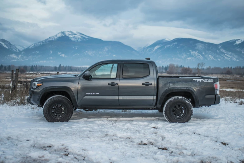 a gray truck on the road in front of some mountains