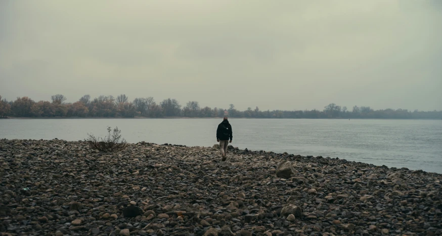 a man in black walking toward a lake