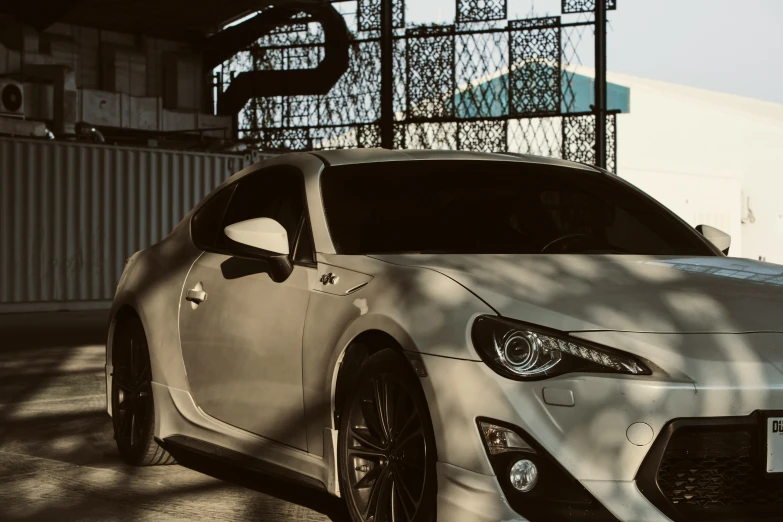 the front end of a white sports car with a shadow