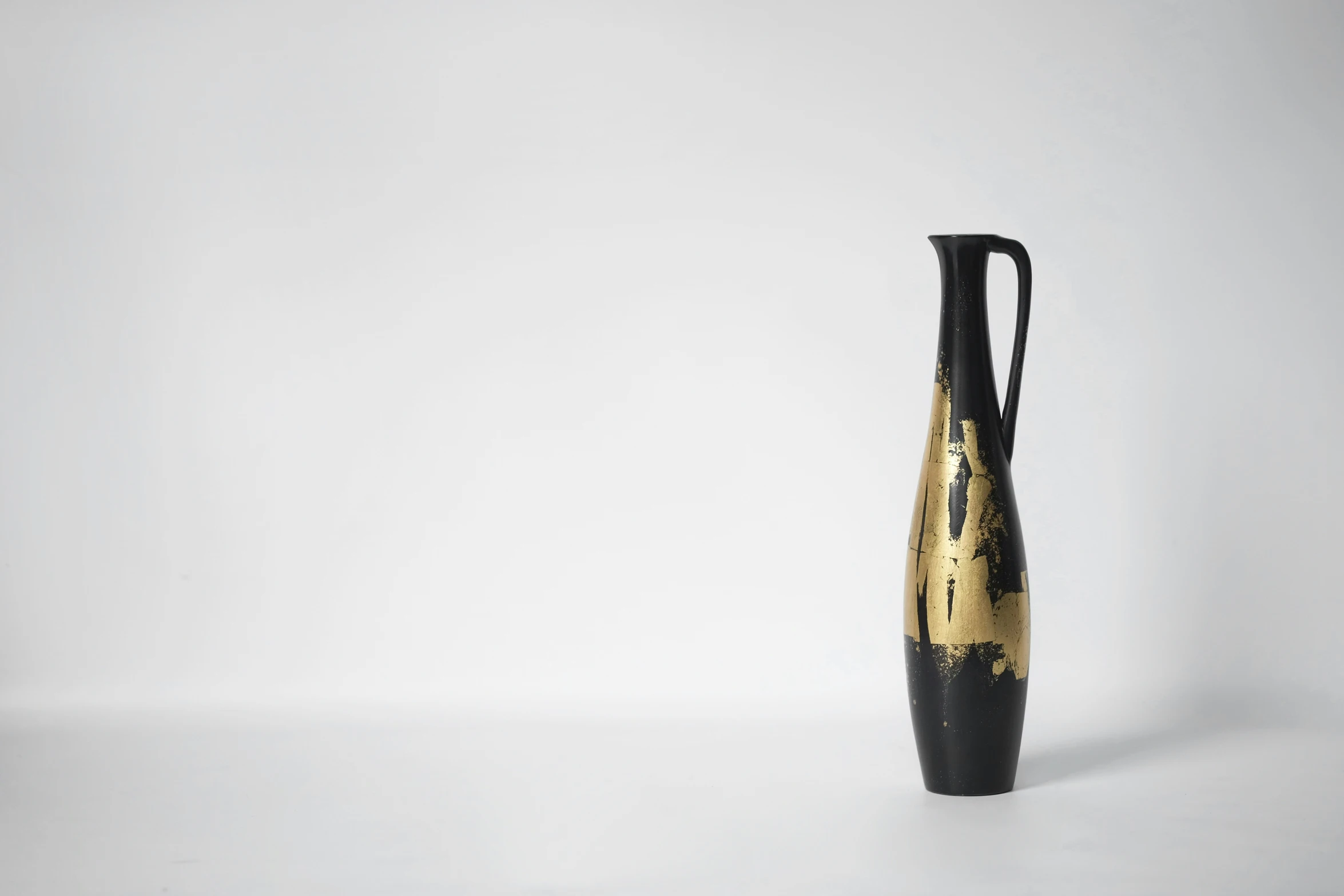 a black and gold vase on a white table